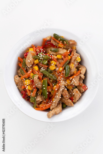 Meat with vegetables and sesame seeds on gray background with yellow cloth