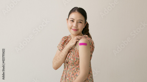 Young attractive beautiful asia female or teenage receive covid-19 anti virus vaccine in campaign vaccination safe life happy smile cheerful with blue, yellow, pink bandage on arm with copy space.