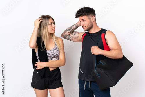 Young sport couple isolated on white background having doubts while scratching head