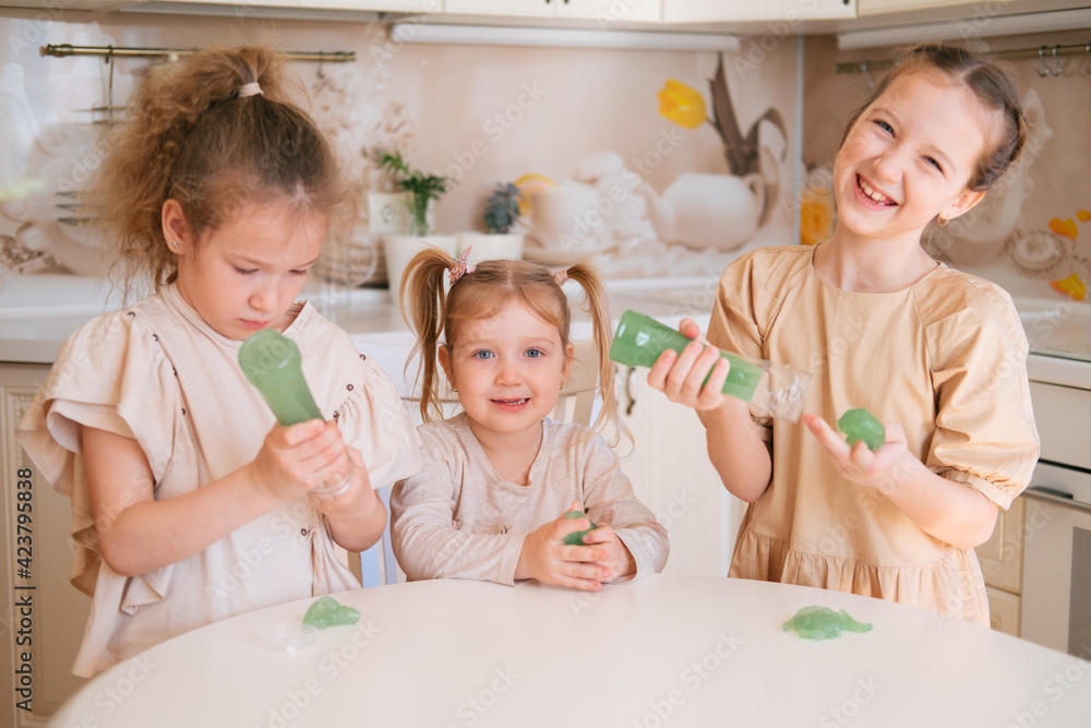 Three sisters playing slime on a kitchen, happy kids lifestyle.