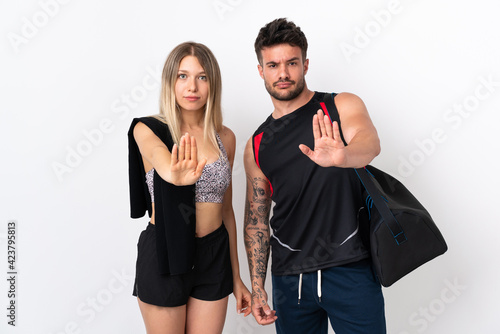 Young sport couple isolated on white background making stop gesture denying a situation that thinks wrong