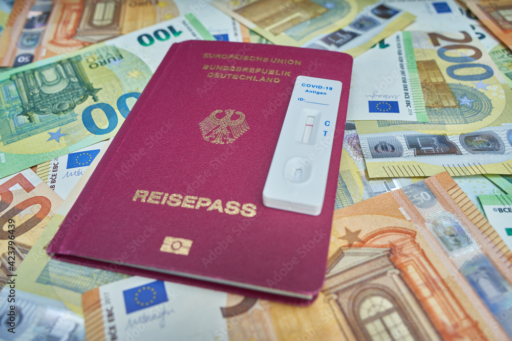 Covid-19 antigen rapid test cassette. Passport for the European Union. Euro banknotes in background. Mandatory testing for travel returnees. ( Testpflicht für Reiserückkehrer ) Germany. Covid-19 antigen rapid test cassette. Passport for the European Union. Euro banknotes in background. Mandatory testing for travel returnees. ( Testpflicht für Reiserückkehrer ) Germany.
