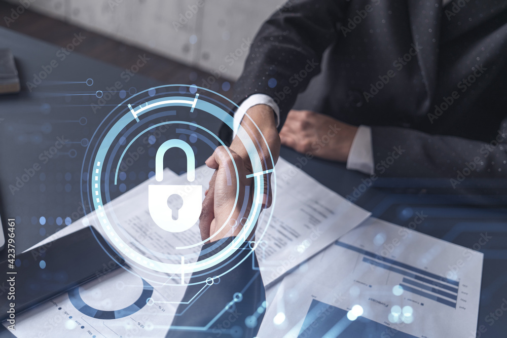 Handshake of two businesswomen who enters into the contract to protect cyber security of international company. Padlock Hologram icons over the table with documents.