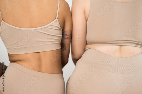 Slika na platnu Strong girl with tattoo sitting near to plus size girl with folds at her body