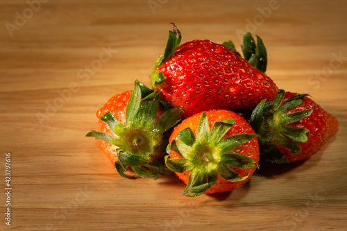 the sweet soft red fruit with a seed-studded surface on the wood. photo