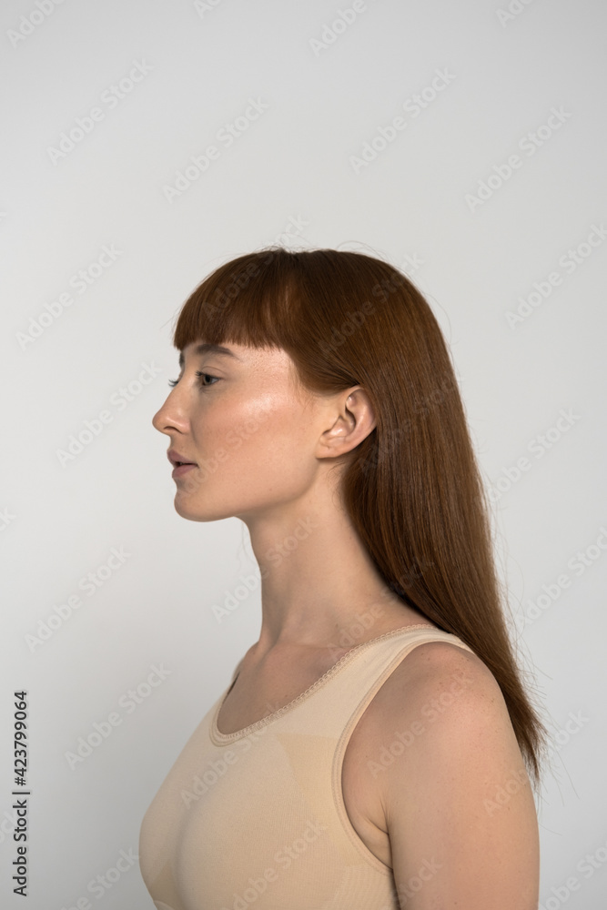 Woman with freckled skin and long ginger hair with bang posing at the studio Woman with freckled skin and long ginger hair with bang posing at the studio