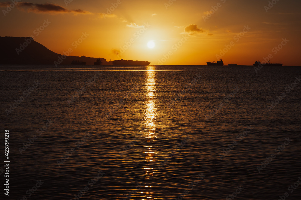 Golden sunrise over the sea and Gibraltar rock. Impressive ships are constantly traveling through the Bay of Algeciras, Andalusia, Southern Spain.