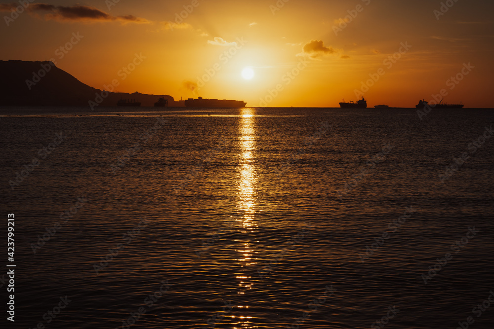 Golden sunrise over the sea and Gibraltar rock. Impressive ships are constantly traveling through the Bay of Algeciras, Andalusia, Southern Spain. Golden sunrise over the sea and Gibraltar rock. Impressive ships are constantly traveling through the Bay of Algeciras, Andalusia, Southern Spain.