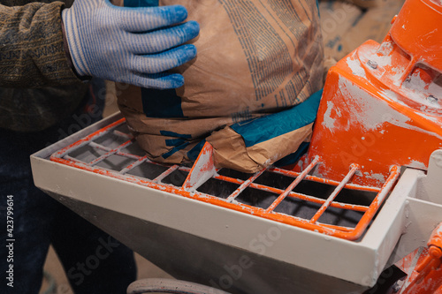 A specialized mixer for mixing dry plaster with water and automatically feeding the finished plaster. A worker pours a bag of dry plaster into the hopper. photo