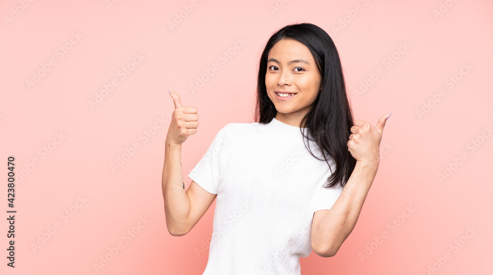 Teenager Chinese woman isolated on pink background giving a thumbs up gesture Teenager Chinese woman isolated on pink background giving a thumbs up gesture