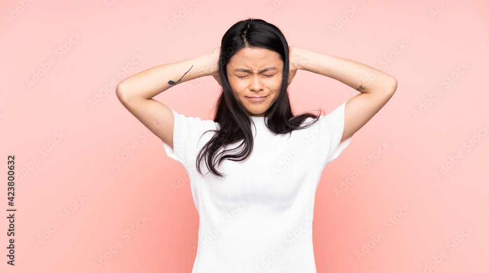 Fototapeta premium Teenager Chinese woman isolated on pink background frustrated and covering ears