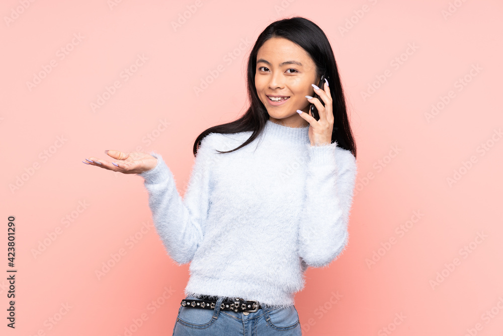 Teenager Chinese woman isolated on pink background keeping a conversation with the mobile phone with someone Teenager Chinese woman isolated on pink background keeping a conversation with the mobile phone with someone
