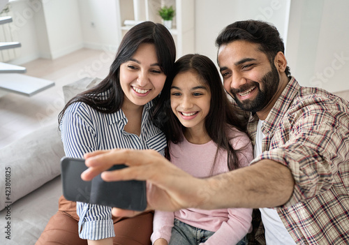 Canvas Print Happy indian family with teen child daughter having virtual call meeting on modern smartphone at home