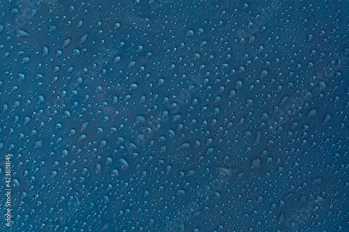 Droplet texture. Wet drop water on glass blue background.