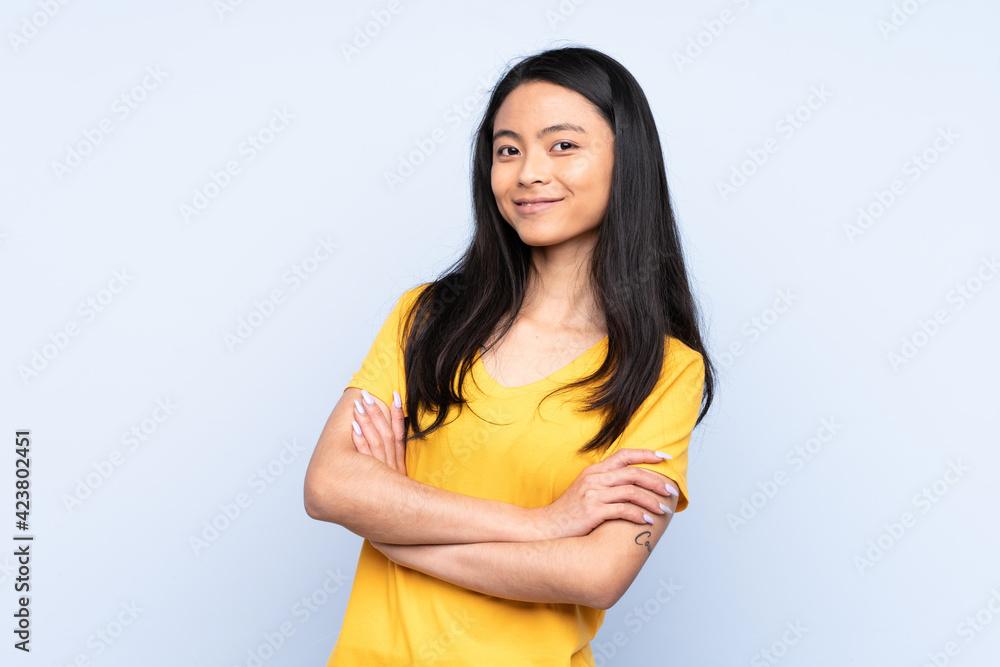Obraz premium Teenager Chinese woman isolated on blue background keeping the arms crossed in frontal position