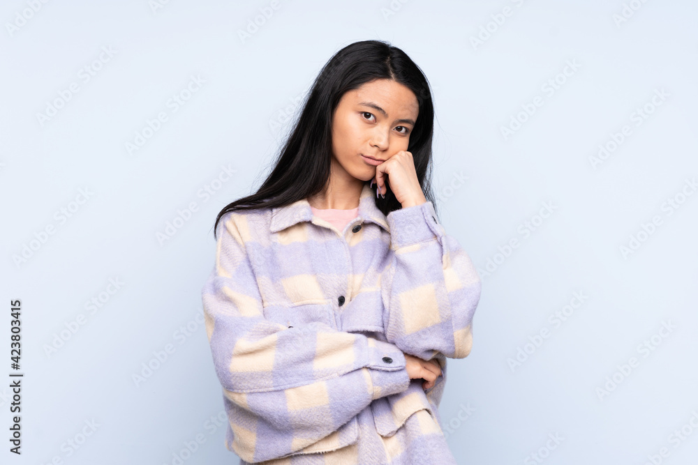 Teenager Chinese woman isolated on blue background with tired and bored expression Teenager Chinese woman isolated on blue background with tired and bored expression