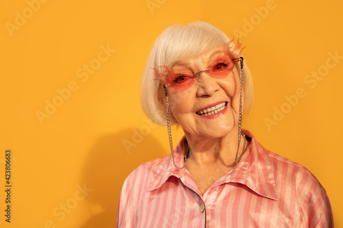 Woman with wrinkled skin smiling toothy and demonstrating perfect emotions