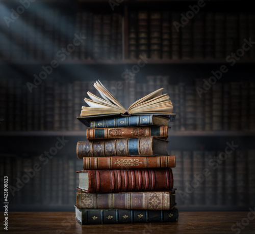 Murais de parede A stack of old books on table against background of bookshelf in library
