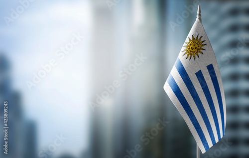 A small flag of Uruguay on the background of a blurred background photo