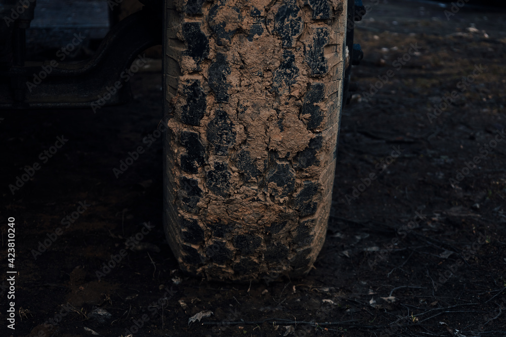 Detail of a off-road tire covered with mud. Close up of dirty car wheel with rubber tire covered with yellow mud. 