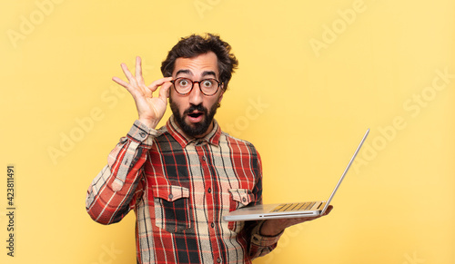 Tableau sur toile young crazy bearded man surprised expression and a laptop