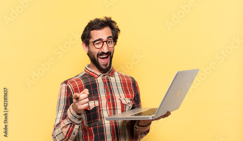 young crazy bearded man pointing or showing and a laptop photo