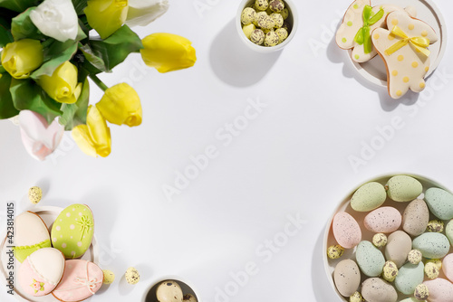 Easter table setting with a plate of colored pastel eggs, a bouquet of tulips and biscuits rabbits,