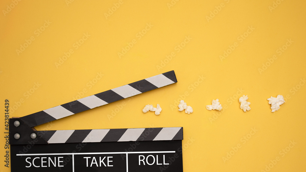 Naklejka premium Cinema Game. Clapperboard Pacman eating popcorn on a yellow background. Top view. Entertainment concept 
