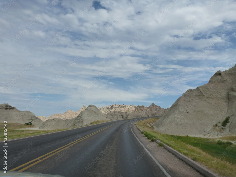 Fototapeta premium A road going through the surreal landscape and terrain at Badlands National Park in South Dakota