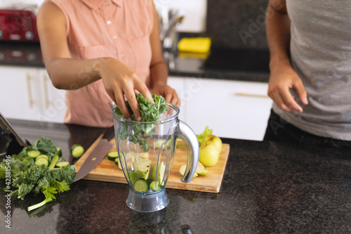 Diverse couple in kitchen making health drink