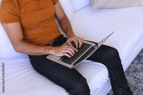 Caucasian man sitting on sofa using laptop