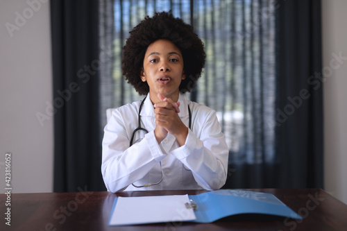 African american female doctor sitting making video call consultation