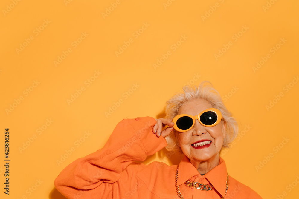 Woman smiling to the camera ​and holding hand at her sunglasses - obrazy, fototapety, plakaty 