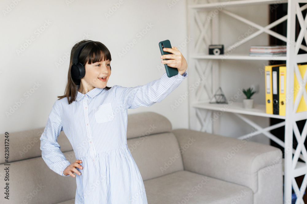 Teen girl at home dancing with headphones in her room with phone Teen girl at home dancing with headphones in her room with phone