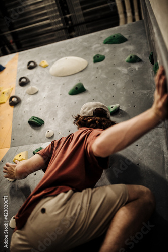 a young man climbing in indoor climbing place in the united states