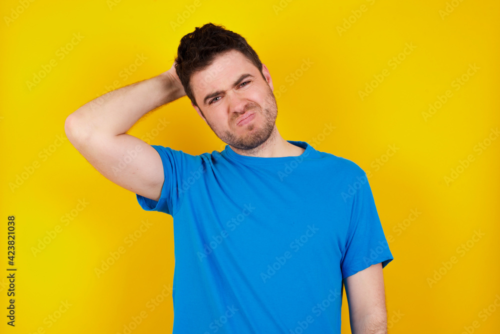 young handsome caucasian man wearing blue t-shirt against yellow background smiling and laughing with hand on face covering eyes for surprise. Blind concept. young handsome caucasian man wearing blue t-shirt against yellow background smiling and laughing with hand on face covering eyes for surprise. Blind concept.