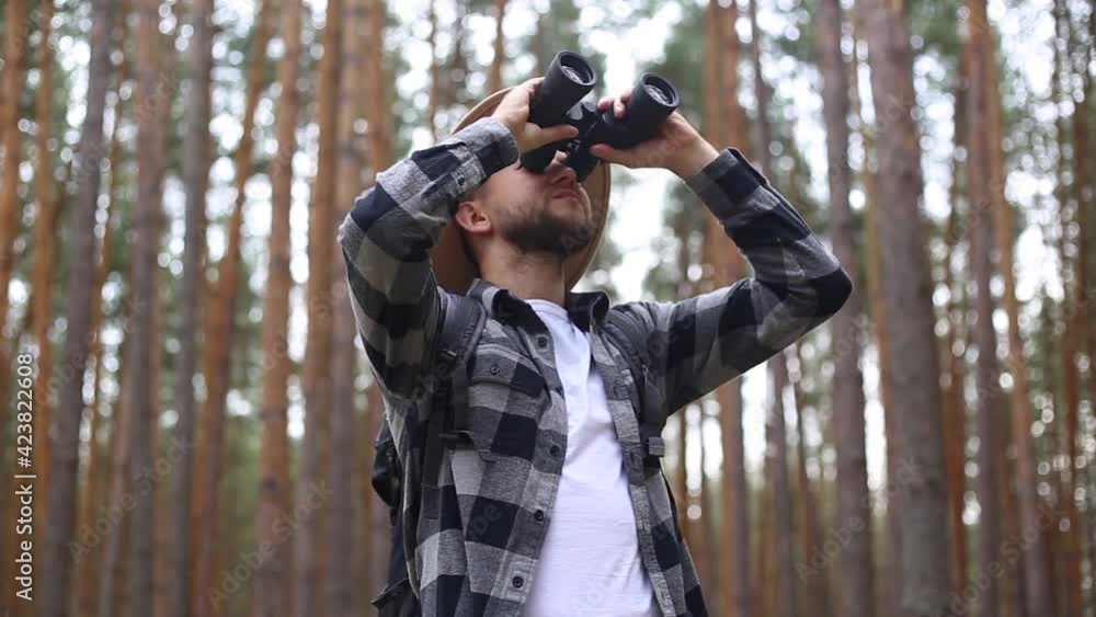 Man tourist with binoculars while hiking in the forest or mountains. Hiking Man tourist with binoculars while hiking in the forest or mountains. Hiking