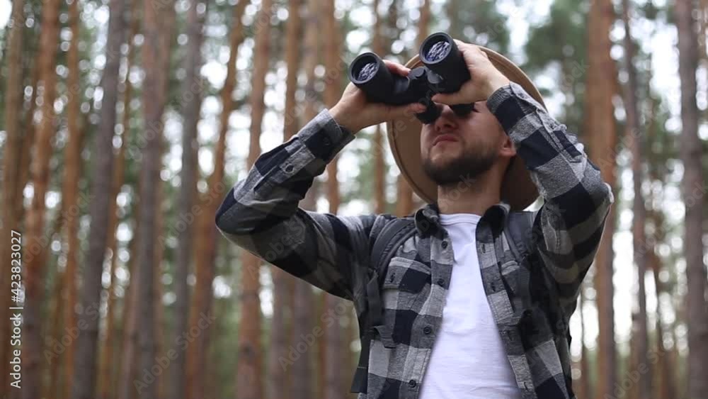 Man tourist with binoculars while hiking in the forest or mountains. Man tourist with binoculars while hiking in the forest or mountains.