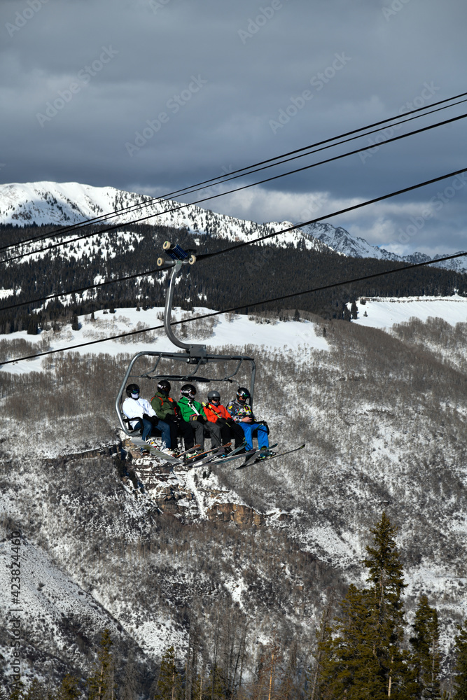 Ski chair lift with skiers and snowboarders. Ski resort in Vail, Colorado, USA