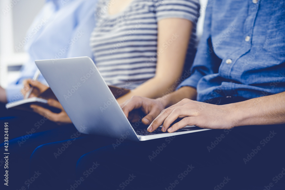 Group of casual dressed business people working at meeting or conference, close-up of hands. Businessman using laptop computer. Teamwork or coaching concept Group of casual dressed business people working at meeting or conference, close-up of hands. Businessman using laptop computer. Teamwork or coaching concept