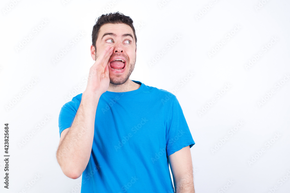 young handsome caucasian man wearing blue t-shirt against white background hear incredible private news impressed scream share young handsome caucasian man wearing blue t-shirt against white background hear incredible private news impressed scream share
