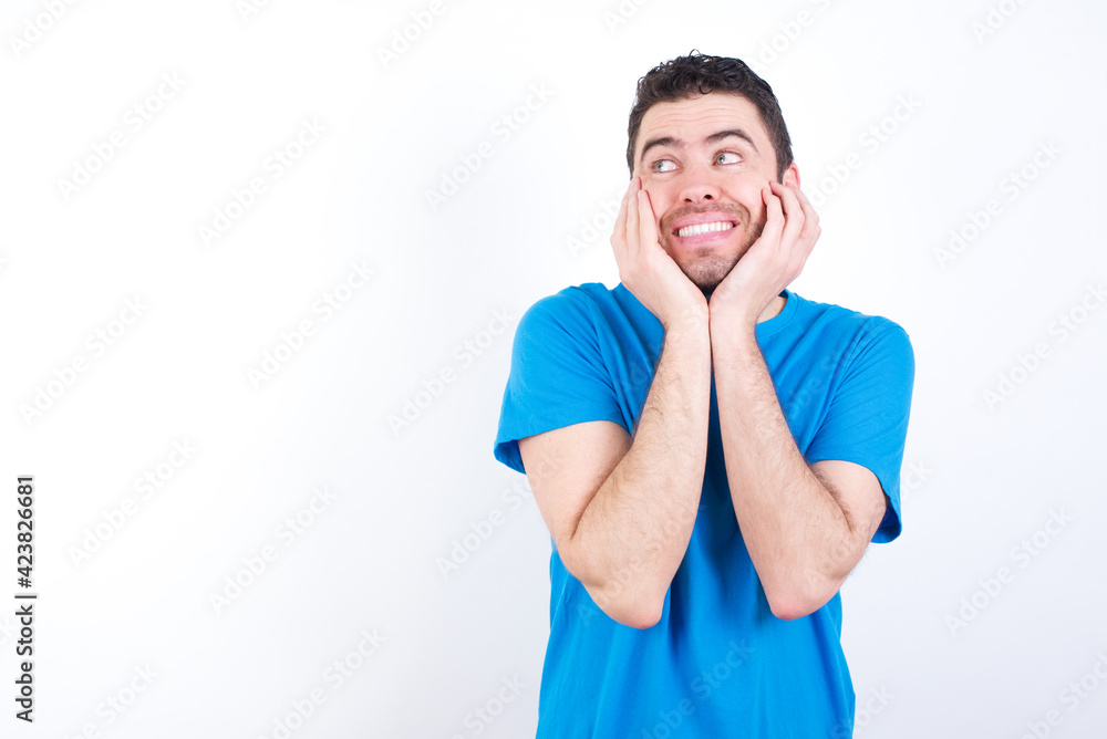 Inspired young handsome caucasian man wearing blue t-shirt against white background looking at copyspace having thoughts about future events Inspired young handsome caucasian man wearing blue t-shirt against white background looking at copyspace having thoughts about future events