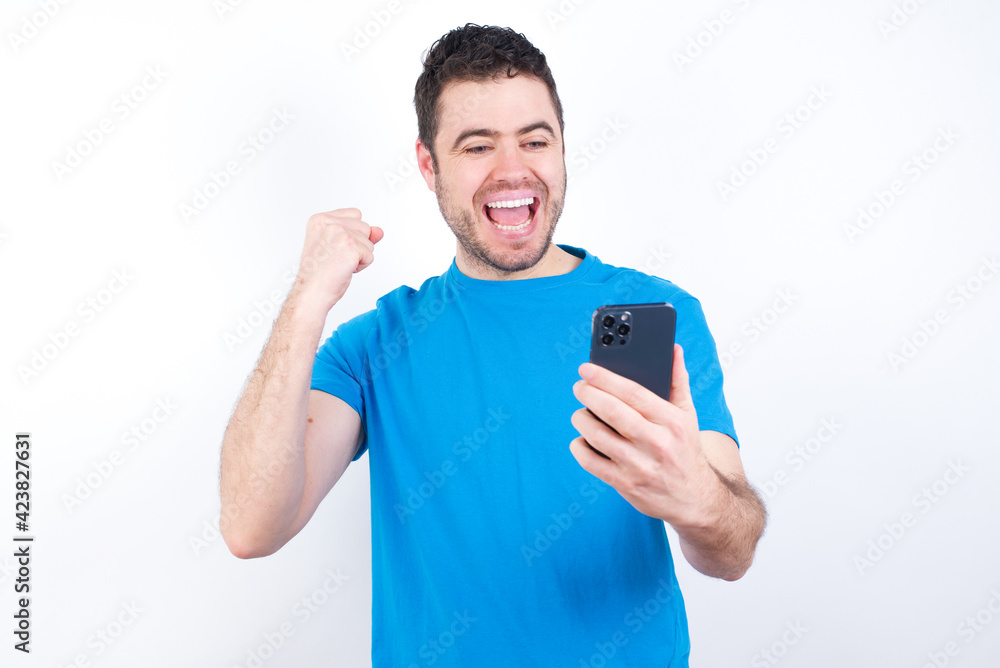 charming cheerful young handsome caucasian man wearing blue t-shirt against white background holding in hands cell reading browsing charming cheerful young handsome caucasian man wearing blue t-shirt against white background holding in hands cell reading browsing