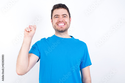 young handsome caucasian man wearing blue t-shirt against white background pointing up with fingers number ten in Chinese sign language Shi
