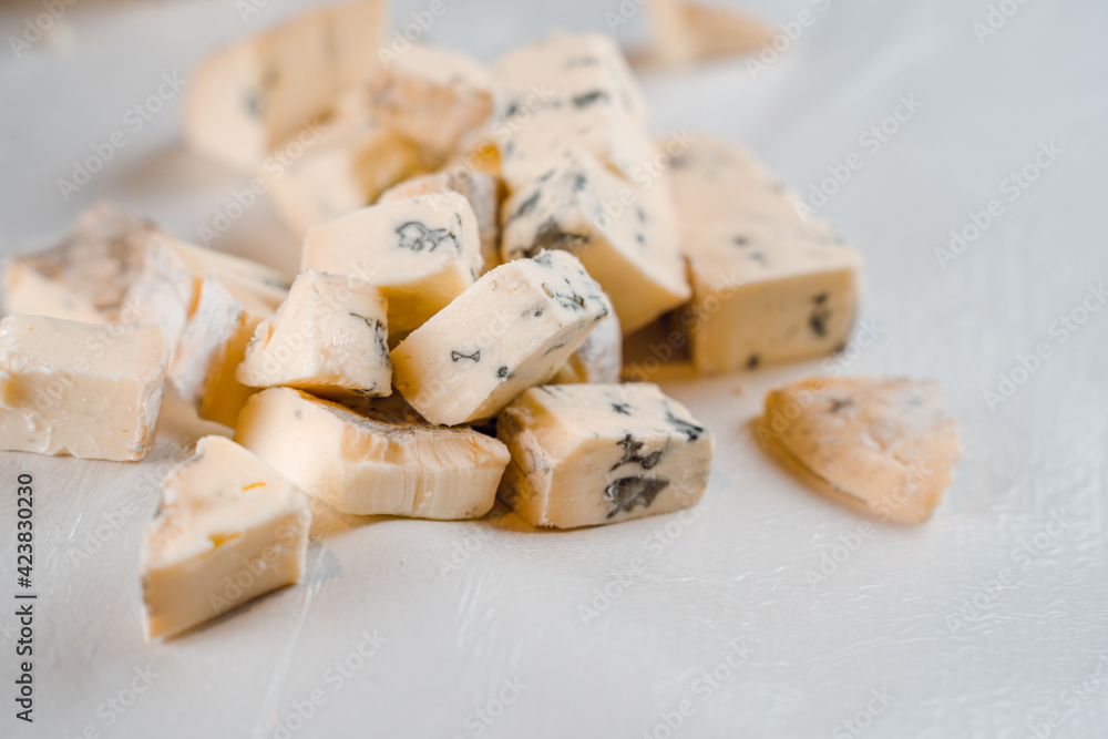 Mix of cheeses on plate. Slicing blue cheese dorblu, gorgonzola, roquefort. French gourmet traditional cuisine. Mix of cheeses on plate. Slicing blue cheese dorblu, gorgonzola, roquefort. French gourmet traditional cuisine.
