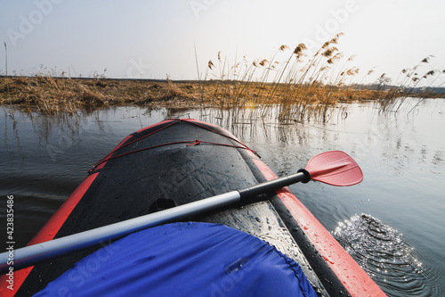 Paddling in red packraft rubber boat on the river at spring. Selective focus. Active lifestile concept. photo