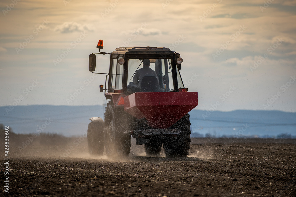 Fototapeta premium Tractor spreading artificial fertilizers