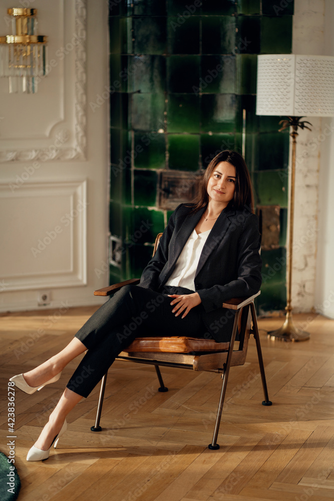 A confident financial lawyer manager. Portrait of a business woman with a brunette European appearance is located in a modern stylish office. Sitting on a chair thinking about work. A confident financial lawyer manager. Portrait of a business woman with a brunette European appearance is located in a modern stylish office. Sitting on a chair thinking about work.