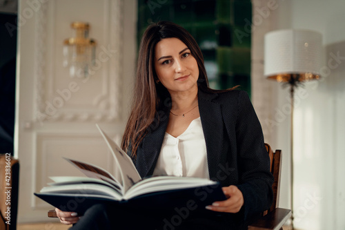  A businesswoman is in a modern, stylish office. Clothing business suit in black. A satisfied finance manager.