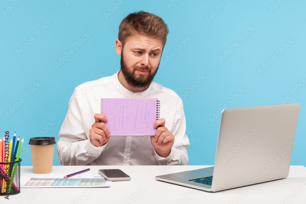 Tired overworked man office worker with beard holding showing notepad with help inscription at camera talking video call with boss, professional burnout. Indoor studio shot isolated on blue background Tired overworked man office worker with beard holding showing notepad with help inscription at camera talking video call with boss, professional burnout. Indoor studio shot isolated on blue background